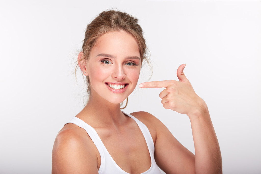 Caucasian woman pointing at her teeth