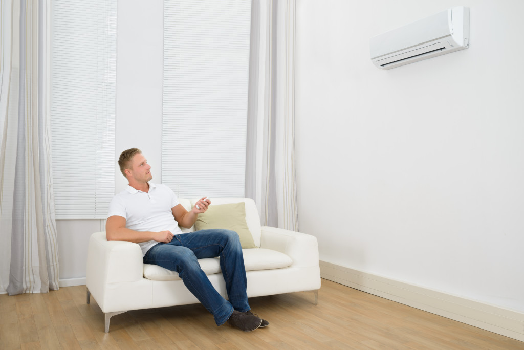 man tuning an air-conditioning unit on while sitting