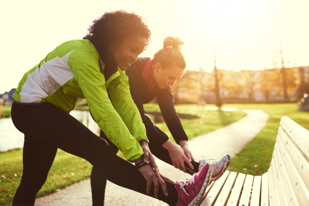 two woman stretching on a bench before going for a run