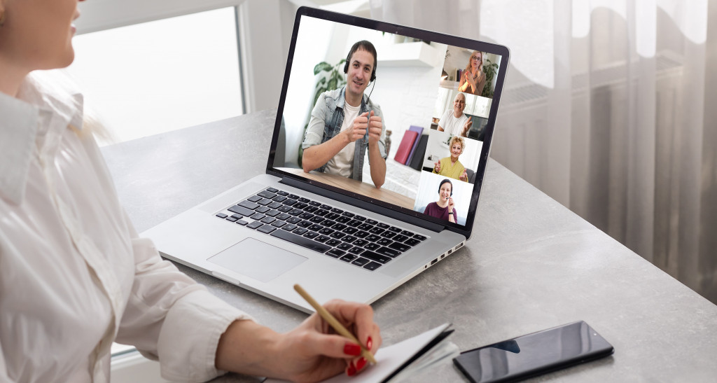 A woman talking to some people while on a video call on her laptop