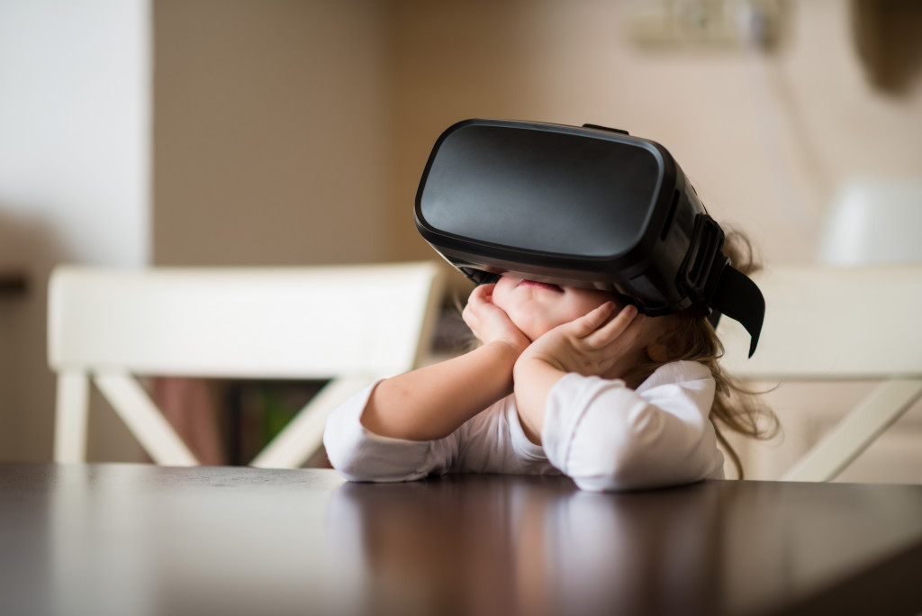 A child wearing a VR headset while sitting behind a table indoors