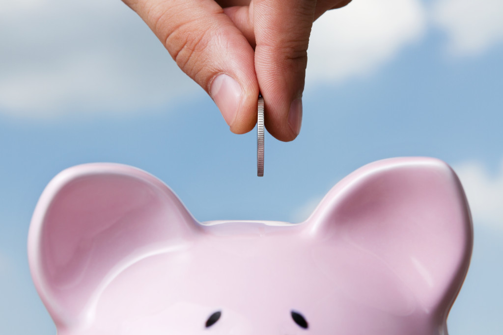 A person putting a coin into a piggy bank