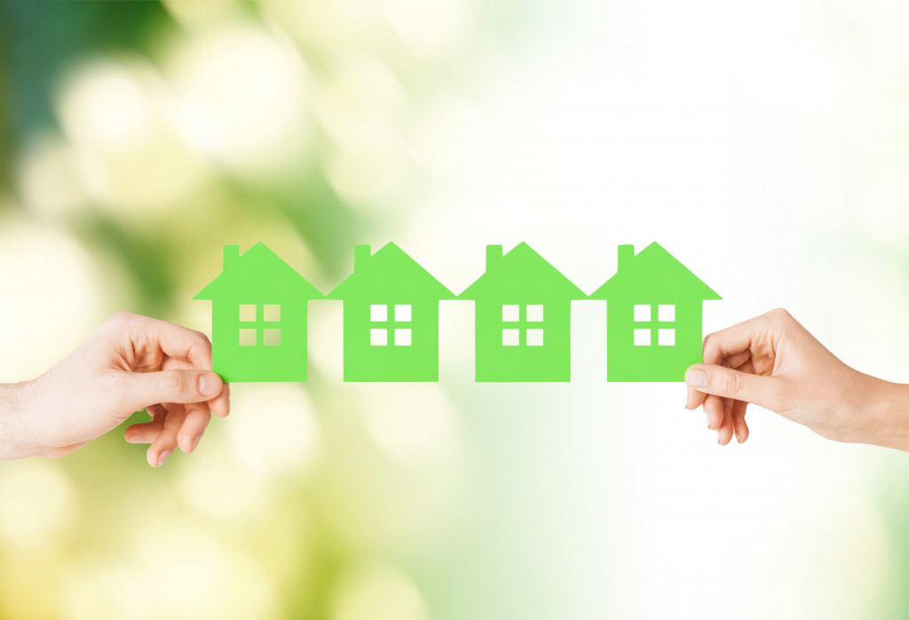 Female hands holding many green paper houses