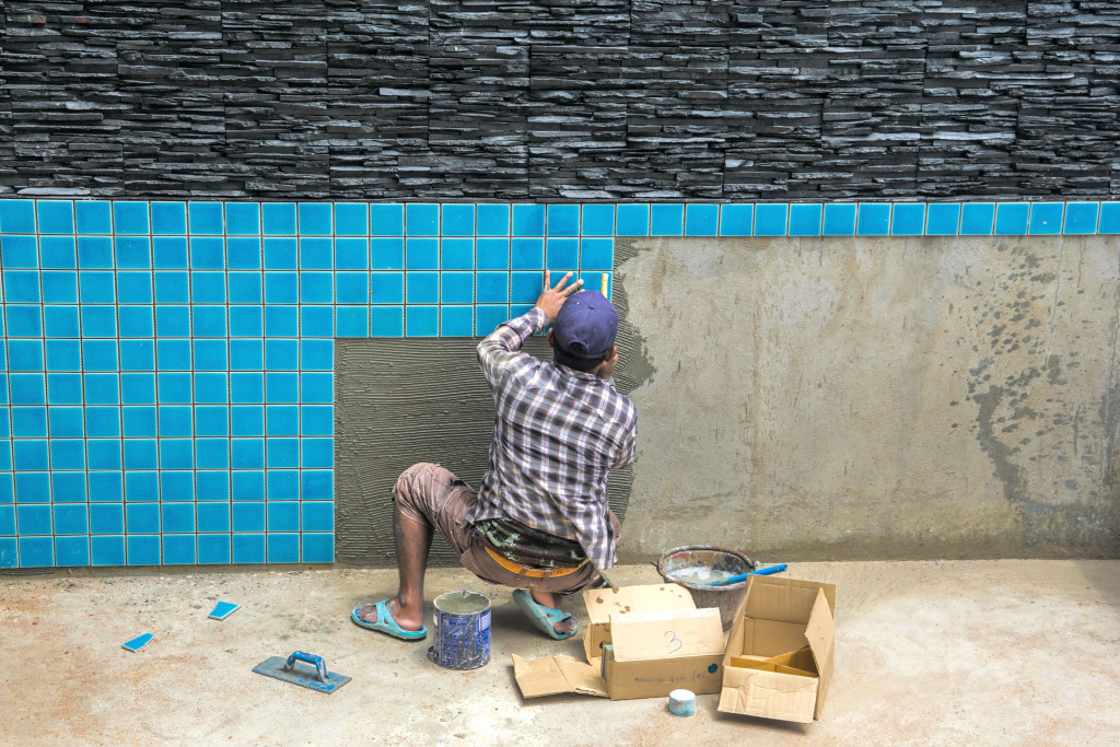 Man putting tiles for a yard pool
