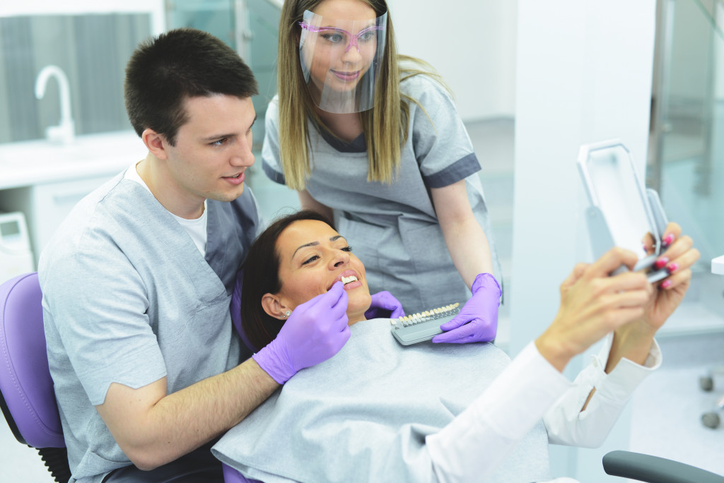 a woman using a mirror to check dental implant 