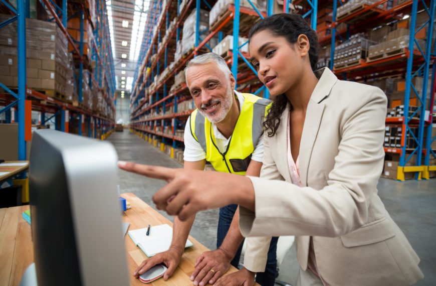a female businesswoman and warehouse personnel looking at a computer